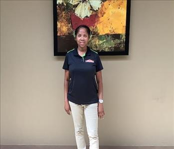 The female employee is attired in the SERVPRO uniform and artwork is in the background 
