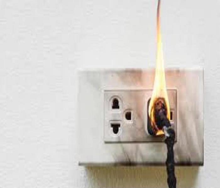 The electrical cord has flames burning while being inserted into the electric socket.