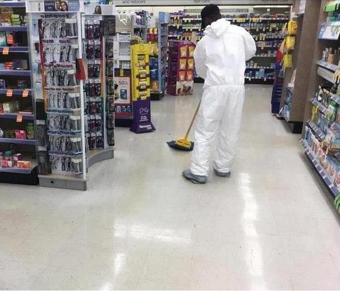 The Technician wears a tyvex suit and cleans up chemical spills in a pharmacy by using a mop.