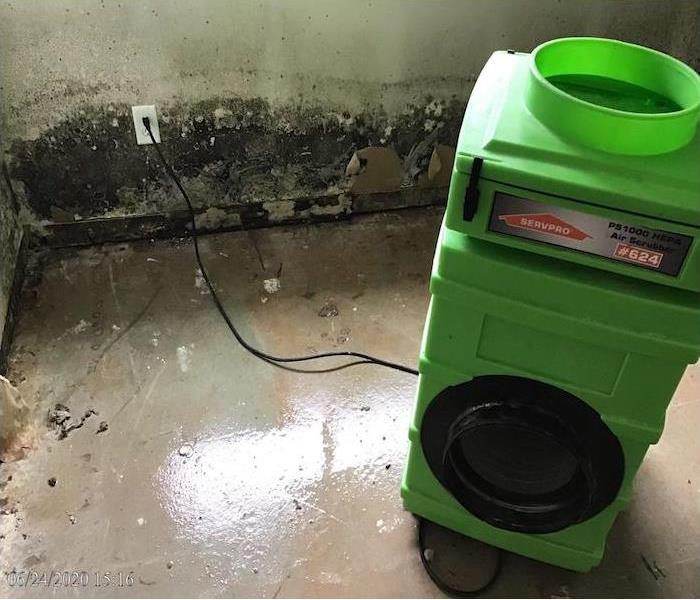 Visible signs of mold display on the wall and floor and an Air Scrubber placed during the Mold Remediation service.