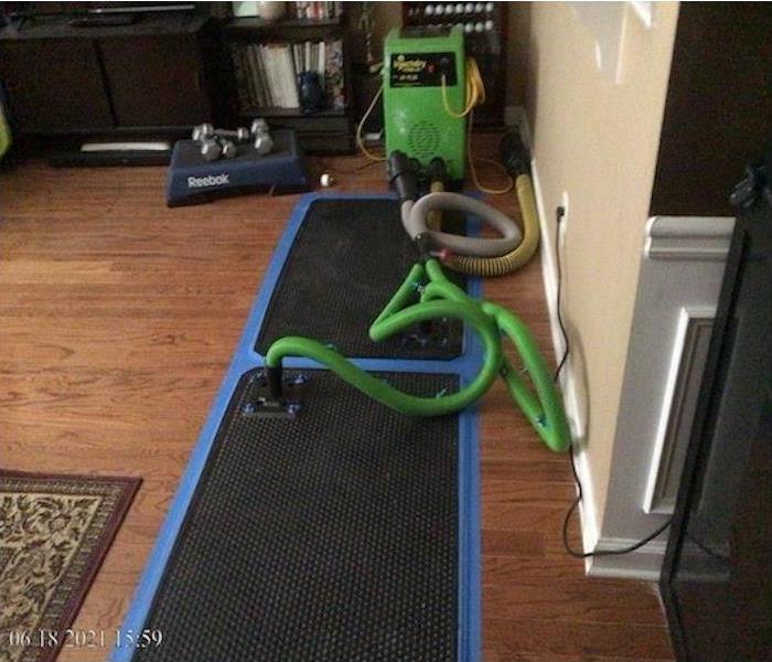 An Injectidry equipment is set up along with its mats to dry the hardwood floor.