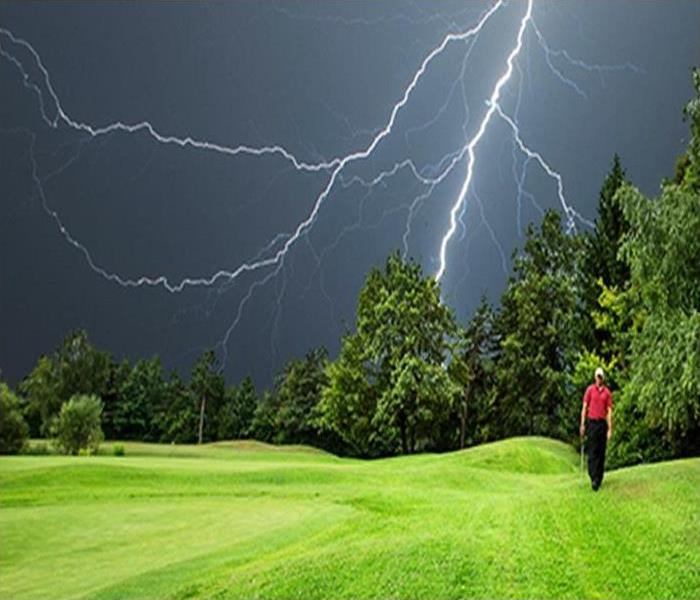 Lightning storms in the sky at a golf course.