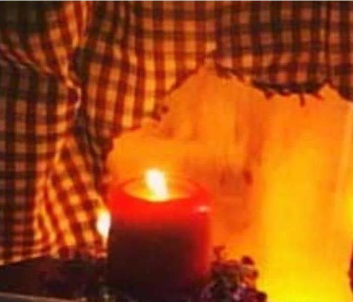 A red candle is lit, and it is near the kitchen curtain.